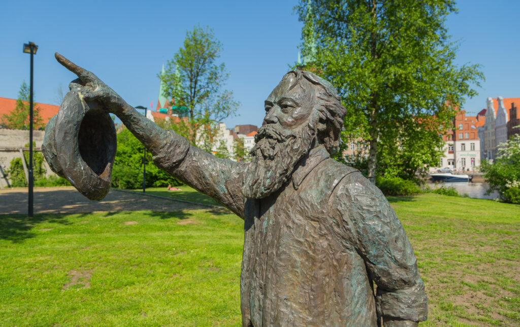 Bronze statue of a bearded Brahms holding his hat and pointing